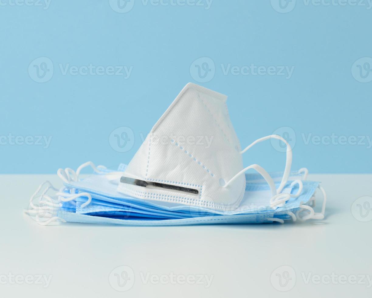 white disposable medical mask on a blue background, personal protective equipment for the respiratory tract from viral infections photo