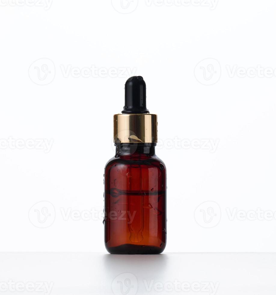 brown glass bottle with a pipette on a white background. Container for cosmetics, oils, serums. Advertising and product promotion photo