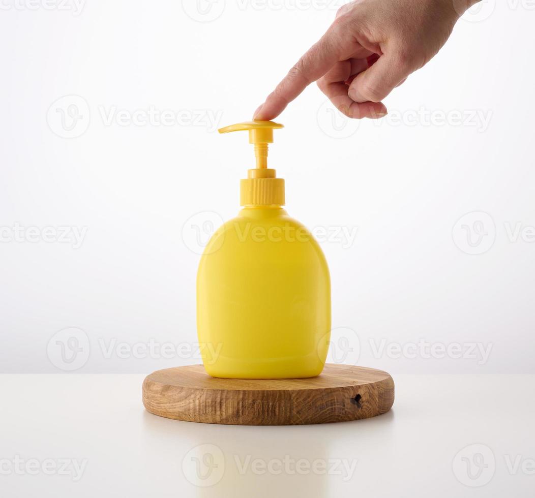yellow plastic container dispenser on a white background. Container for liquid soap, shampoo photo