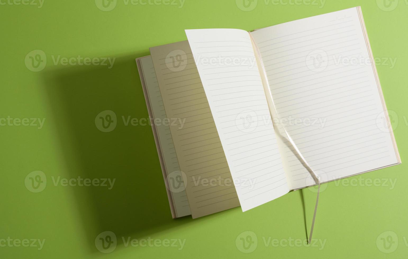 open notebook with blank white sheets on green background photo
