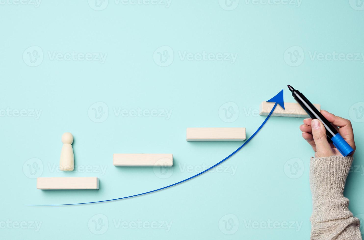 Wooden man and steps. A woman's hand drew an arrow with a blue marker. Career growth concept, successful business start photo