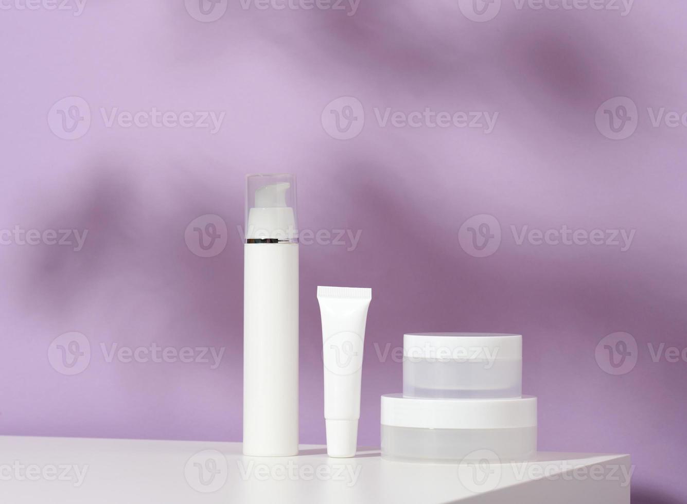 frasco y tubos de plástico blancos vacíos para cosméticos sobre un fondo morado. embalaje para crema, gel, suero, publicidad y promoción de productos, maqueta foto