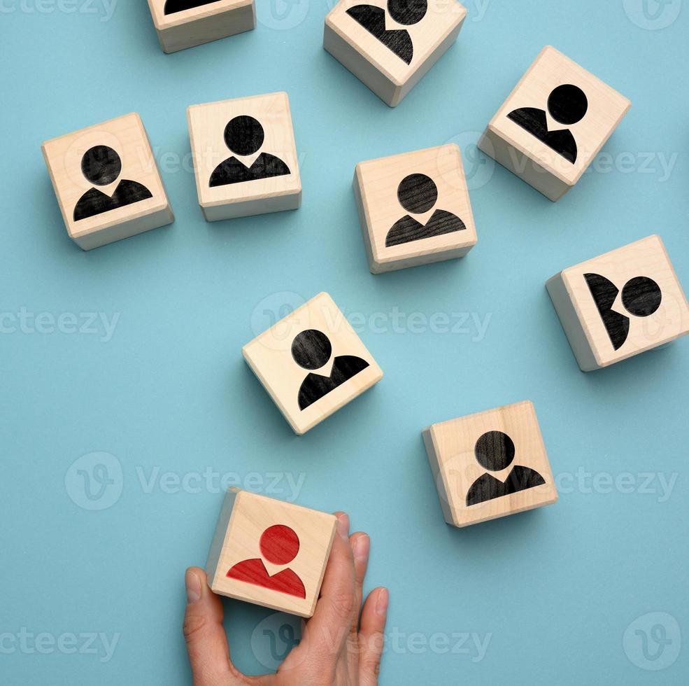 female hand holds a wooden block on a blue background. Recruitment concept, teamwork, effective management photo
