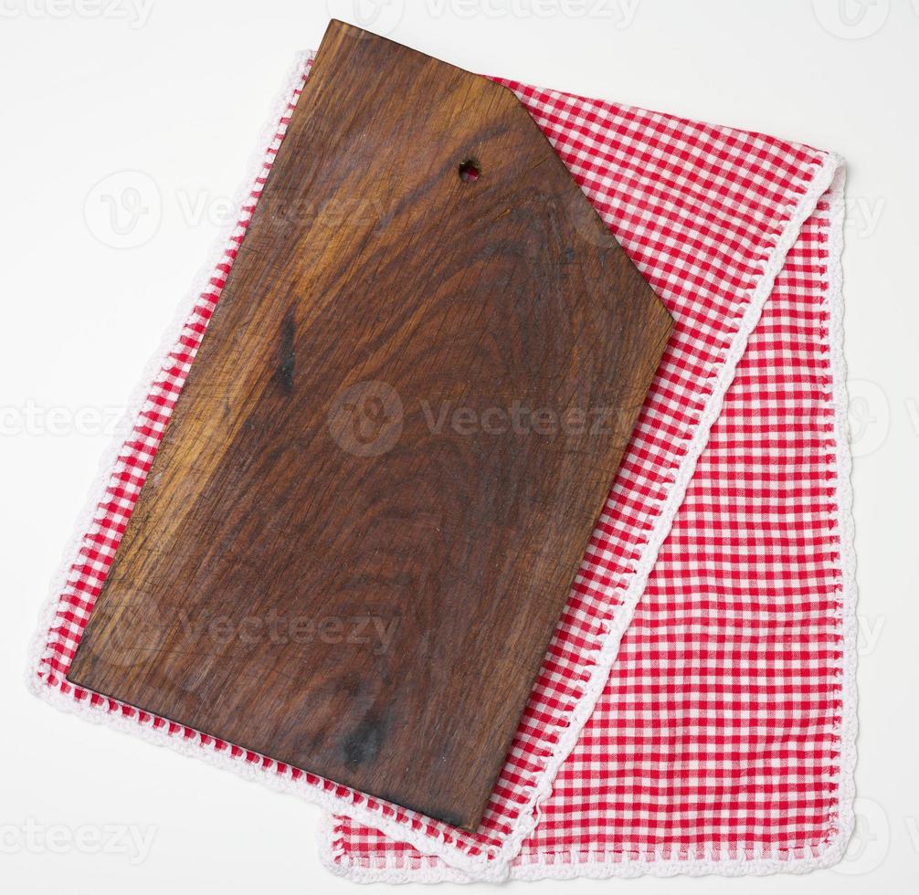 empty rectangular wooden kitchen cutting board and red towel in a white cage on a white table, top view photo