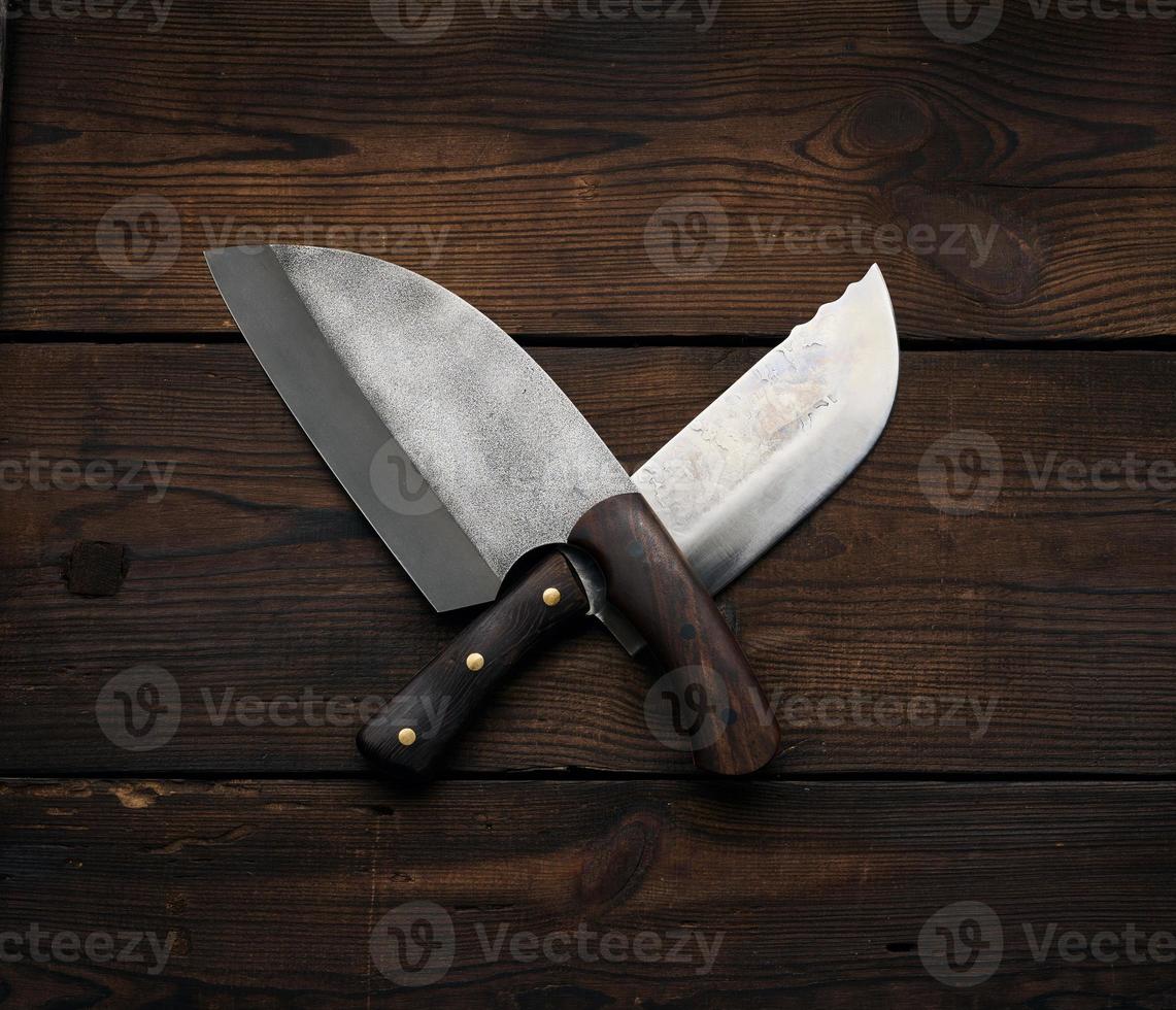 metal sharp kitchen knives in a wooden handle on a brown table made of boards, top view photo