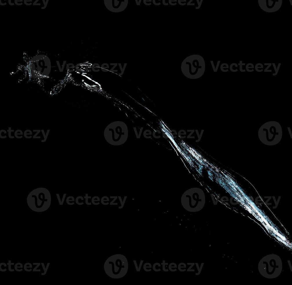 jet of transparent water with small drops and splashes on a black background photo