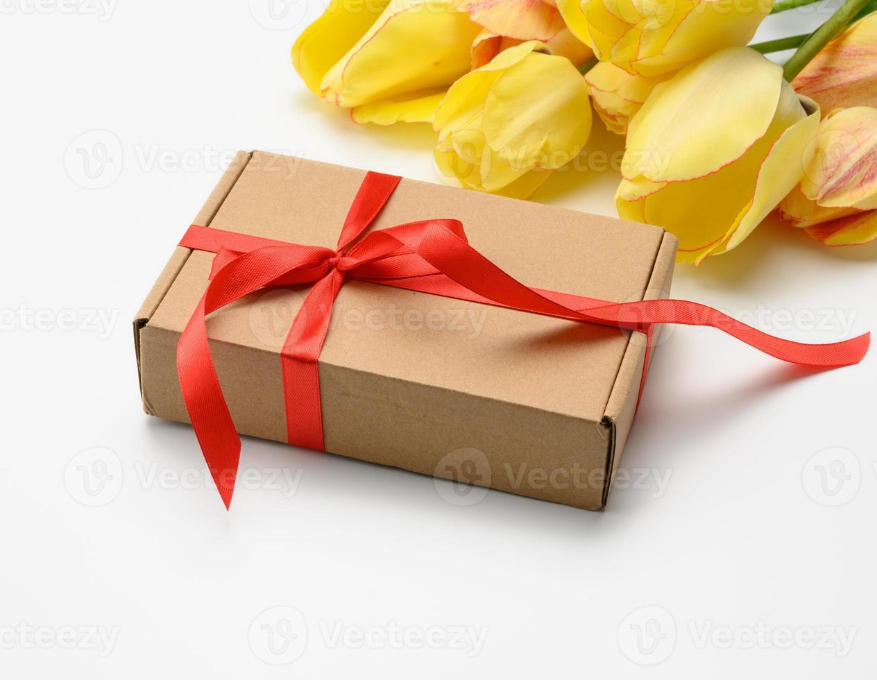 yellow tulips and square box tied with red ribbon on white background, festive background for mother's day photo