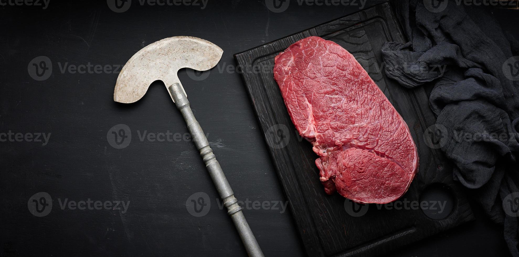 Raw beef tenderloin lies on a cutting board on a black table, top view photo