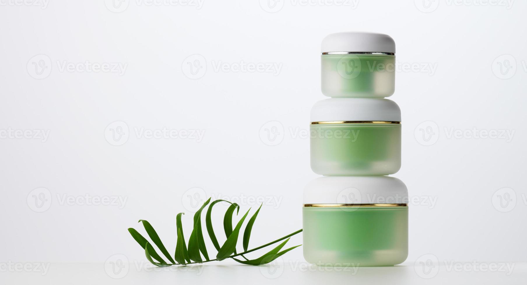 tarro verde para cosméticos sobre una mesa blanca. envases para crema, gel, suero, publicidad y promoción de productos foto