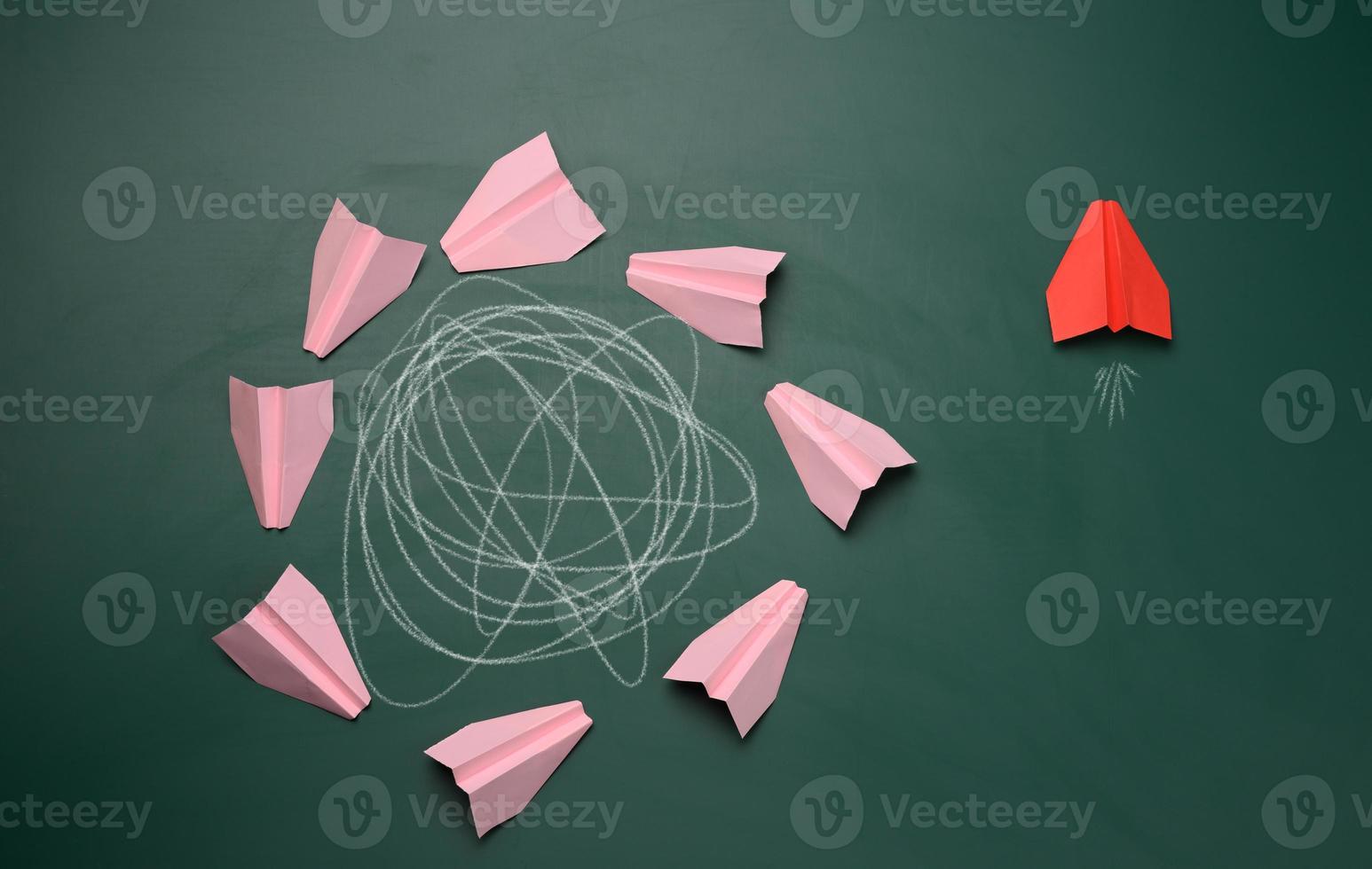 group of pink planes fly in a circle with an intricate trajectory and one flies in a straight path. The concept of thinking outside the box, uniqueness. photo