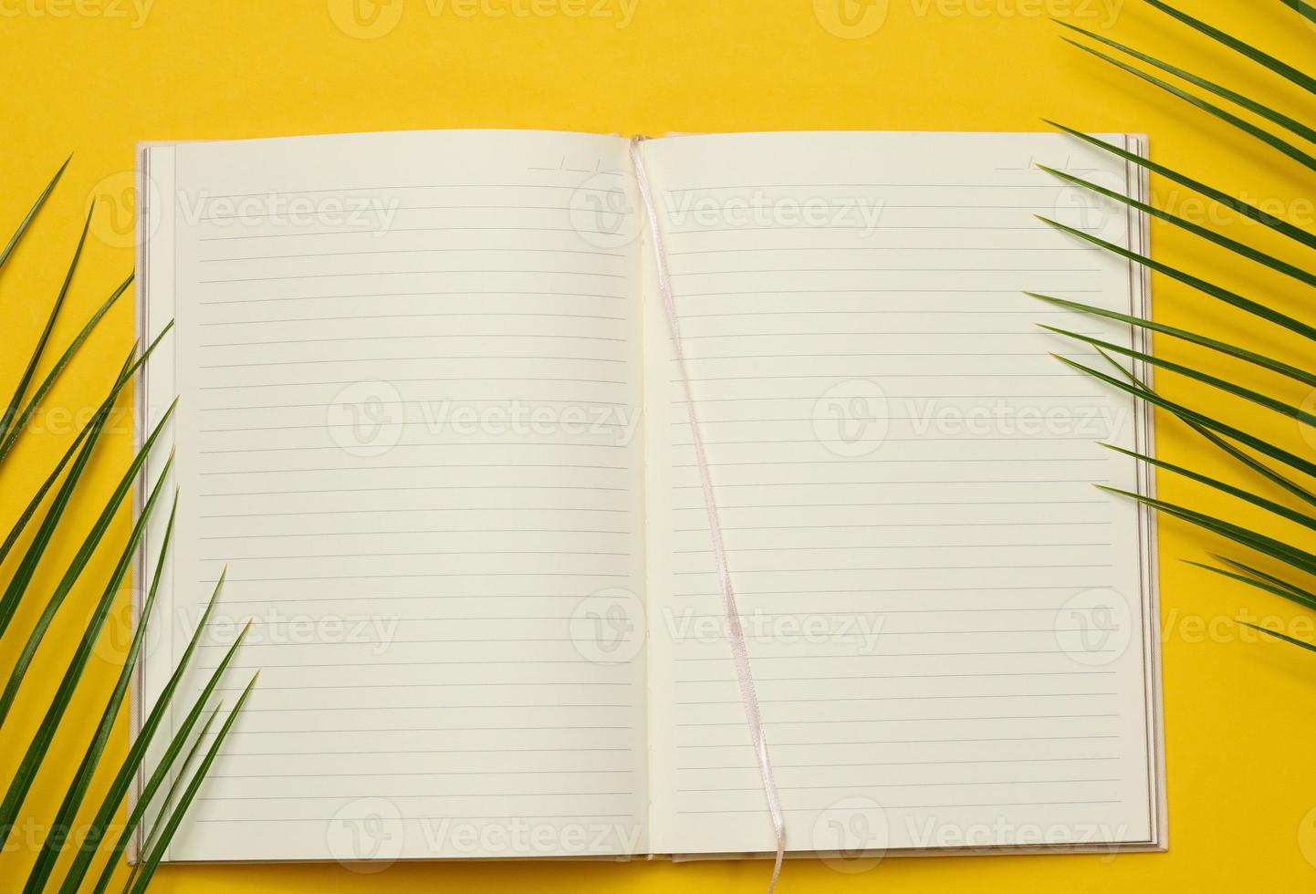 open notebook with blank white sheets on a yellow background, top view. photo