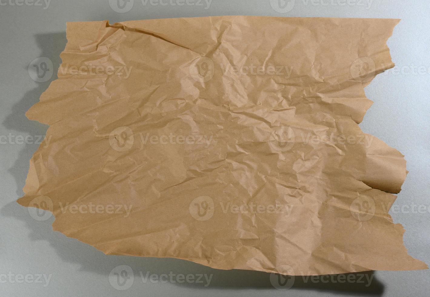 mint brown piece of paper with torn edges and shadow on gray background photo