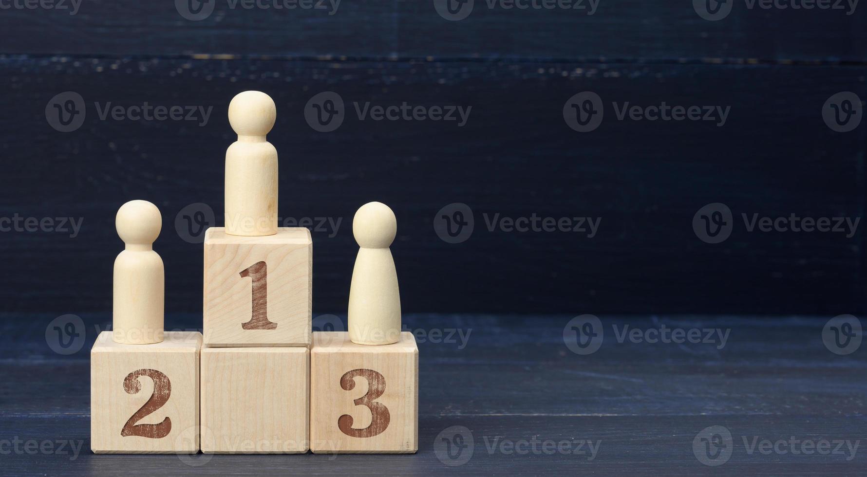 wooden figures of men stand on a pedestal of their cubes on a blue background. The concept of rivalry in sports, business and life photo