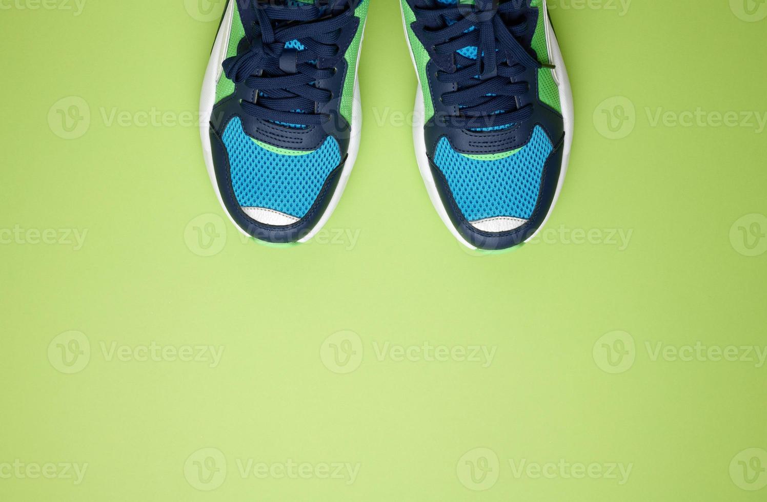 pair of blue textile sneakers on a green background, top view. Shoes for sports photo