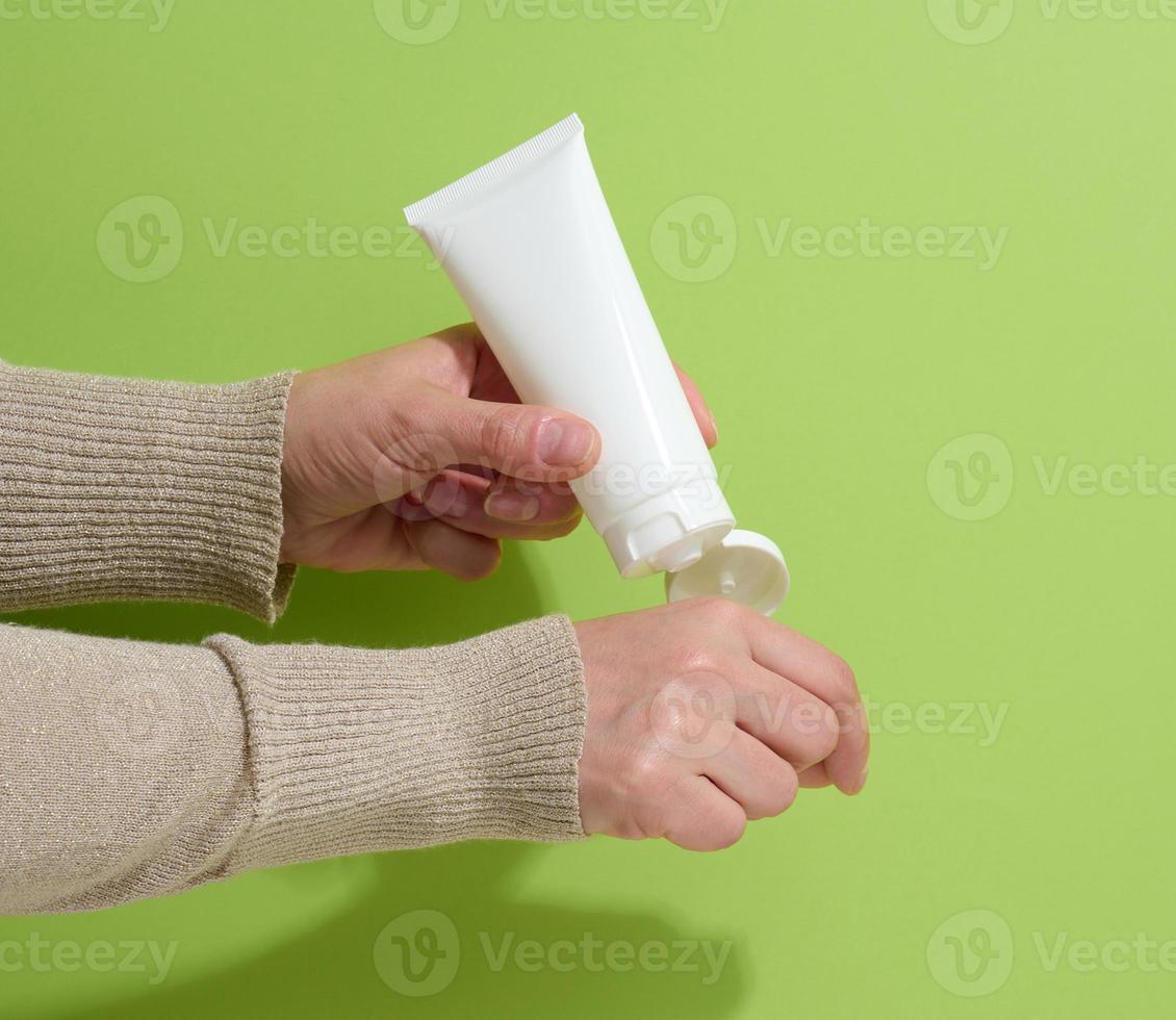 female hand holds empty white plastic tubes for cosmetics. Packaging for cream, gel, serum, advertising and product promotion, mock up photo