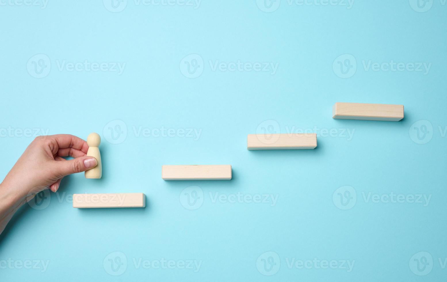 wooden steps and a figurine of a little man in a woman's hand. Startup, starting a new successful business, achieving goals photo