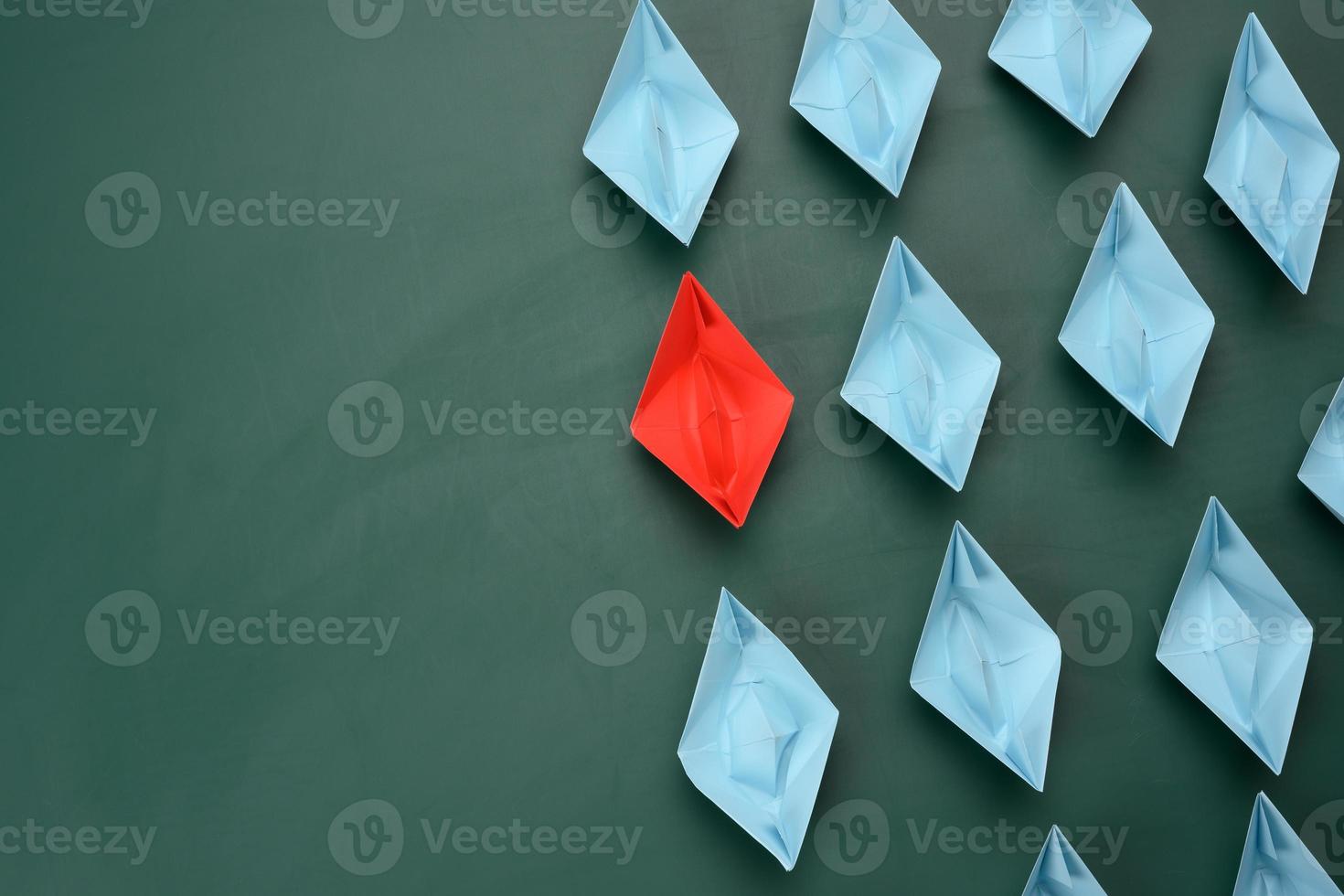 group of paper boats on a green background. concept of a strong leader in a team, manipulation of the masses, following new perspectives, collaboration and unification photo