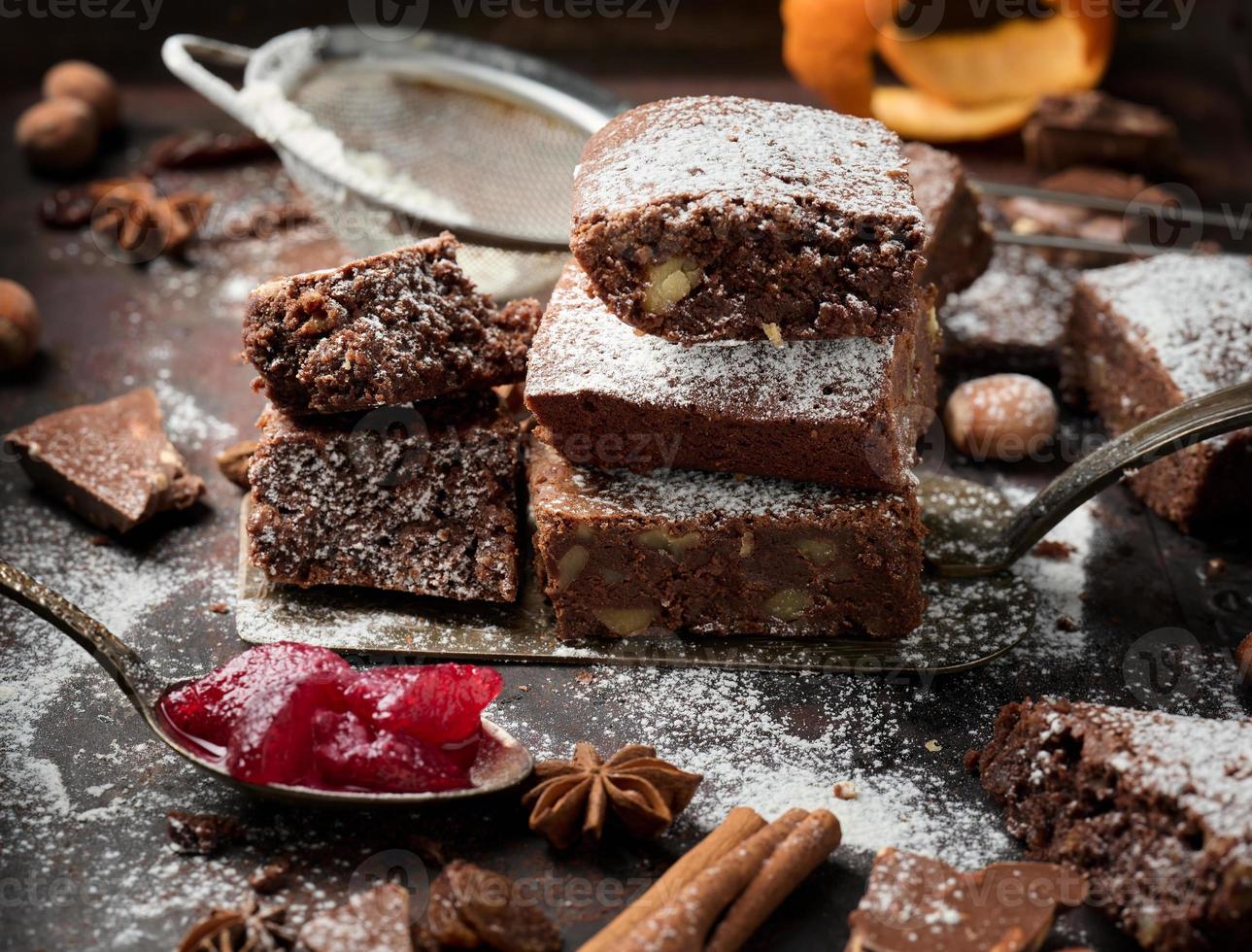 baked square pieces of chocolate brownie sprinkled with powdered sugar on the table photo