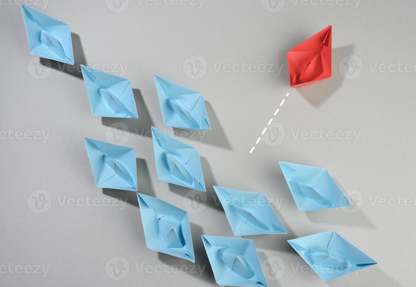 group of paper boats on a gray background. The concept of thinking outside the box, uniqueness. photo