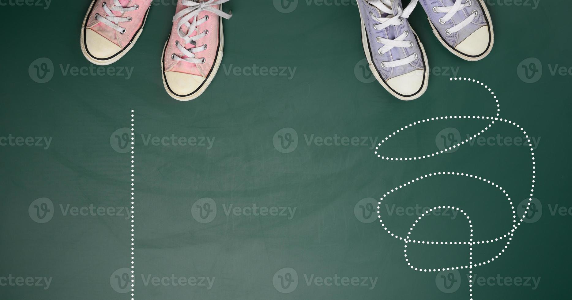 two pairs of textile sneakers on a green background. The concept of choosing a path is difficult and confusing or straight and easy photo