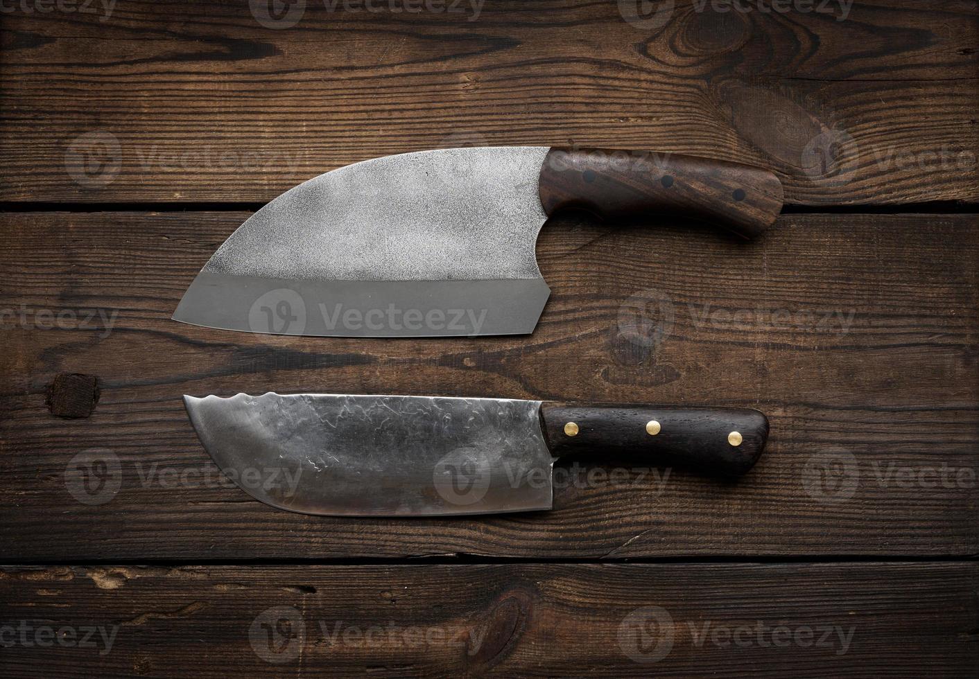 metal sharp kitchen knives in a wooden handle on a brown table made of boards, top view photo