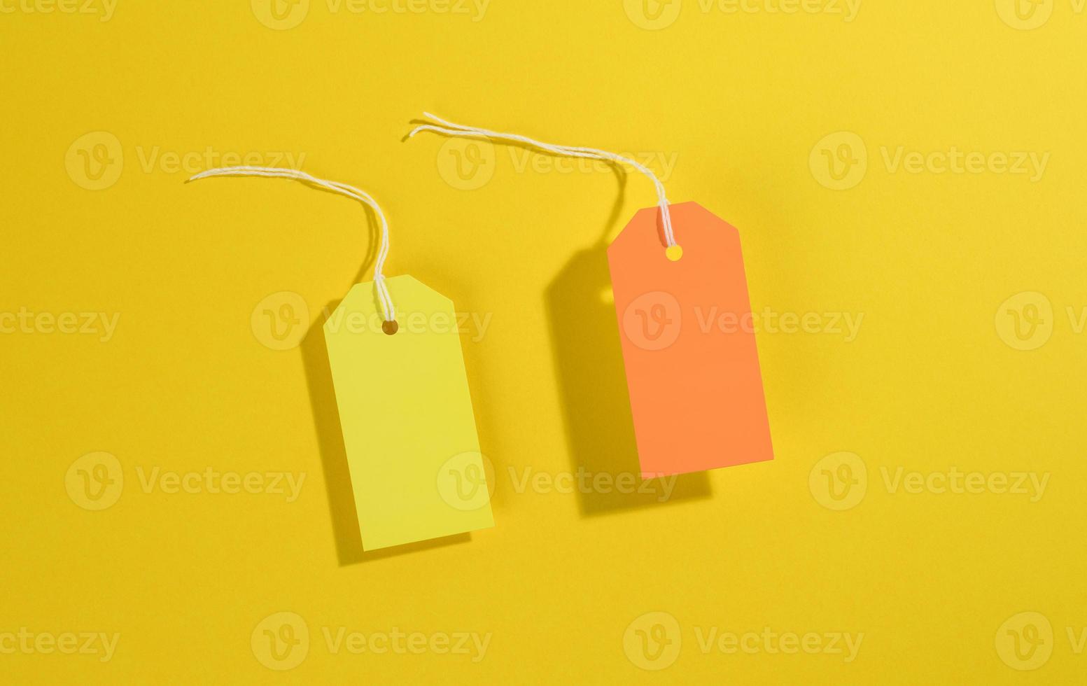 blank rectangular paper yellow and orange price tags with white rope on yellow background photo