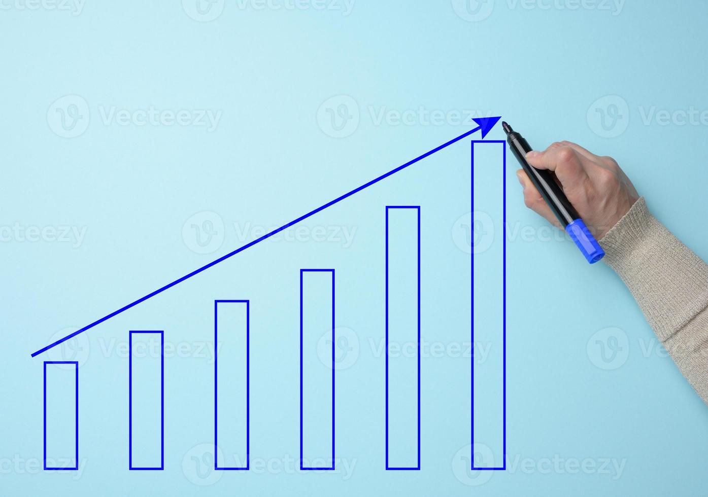 Graph with growing indicators and a female hand with a marker on a blue background. The concept of successful sales in business, inflation and rising prices photo