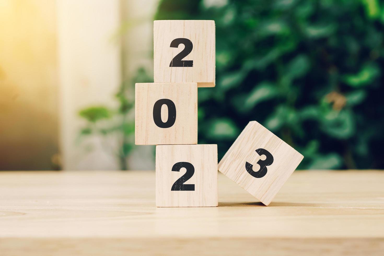 2023 happy new year on wood block on wood table with sunlight. new year concept. photo