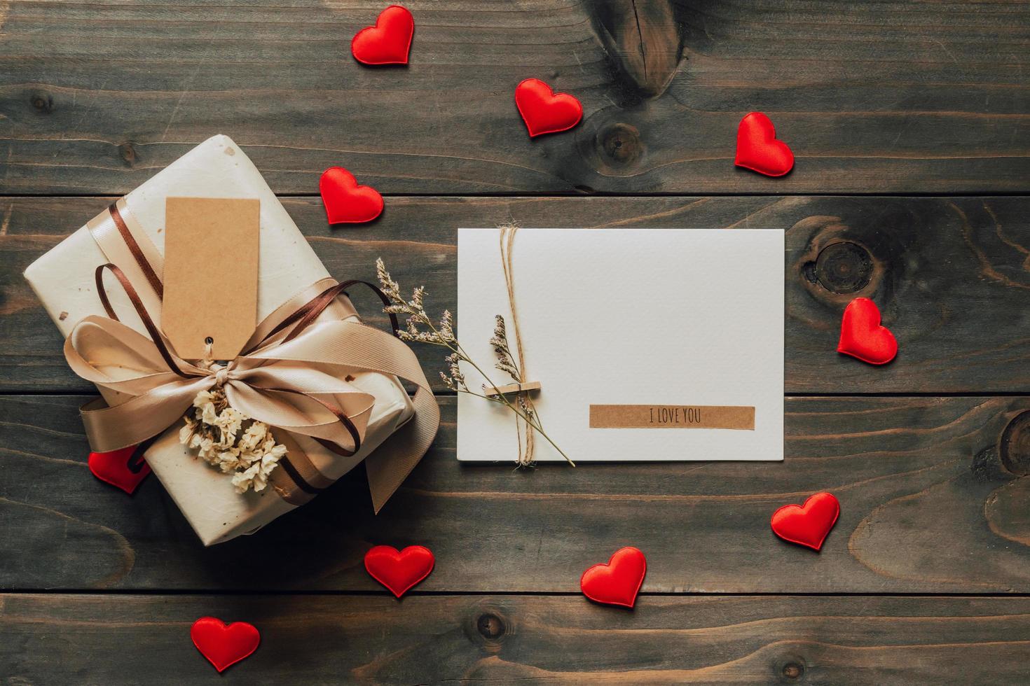 Gift box and greeting card with bow ribbon and paper hearts on wooden table for Valentines day. copy space. photo