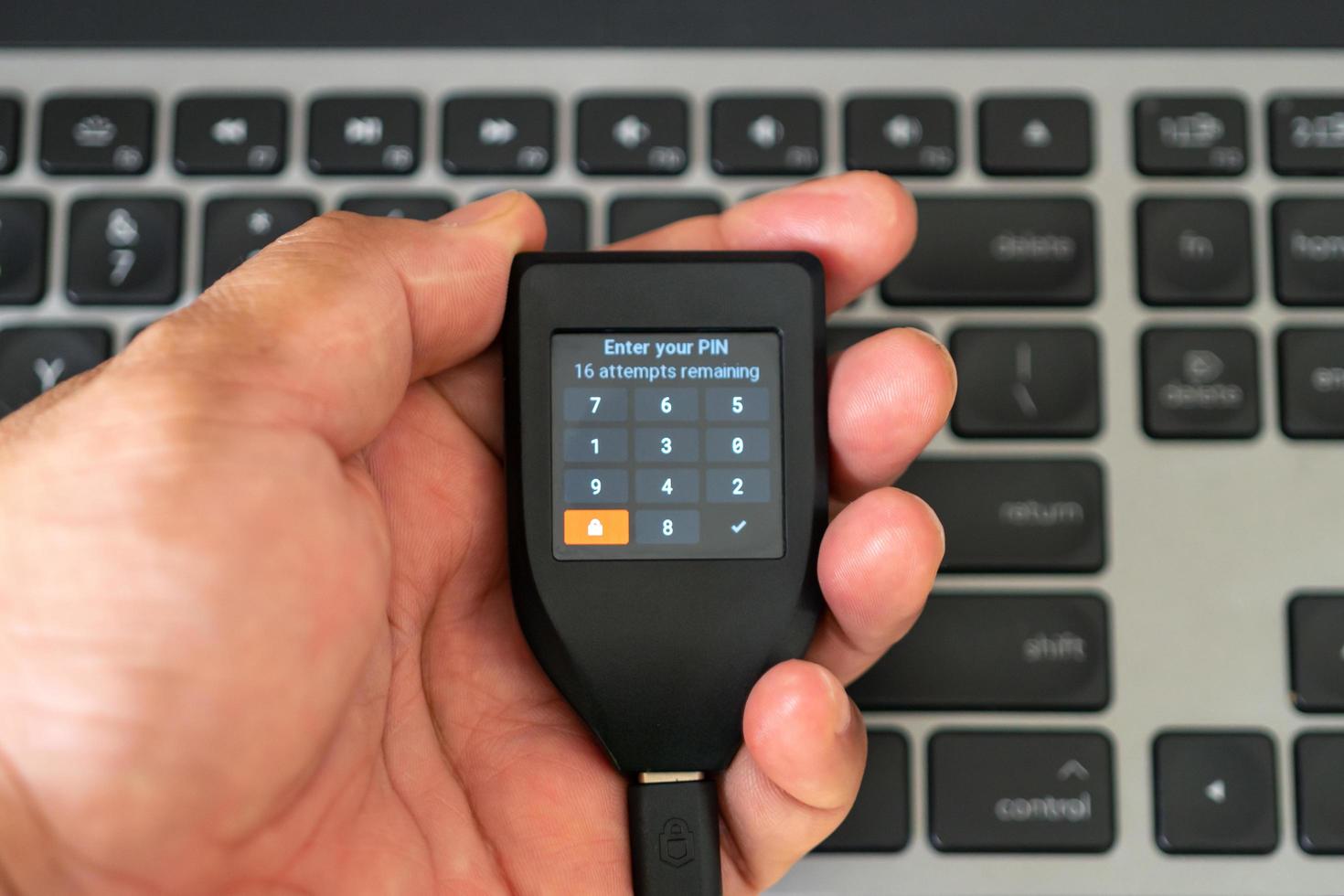 Holding hardware wallet on hand and typing pin code photo