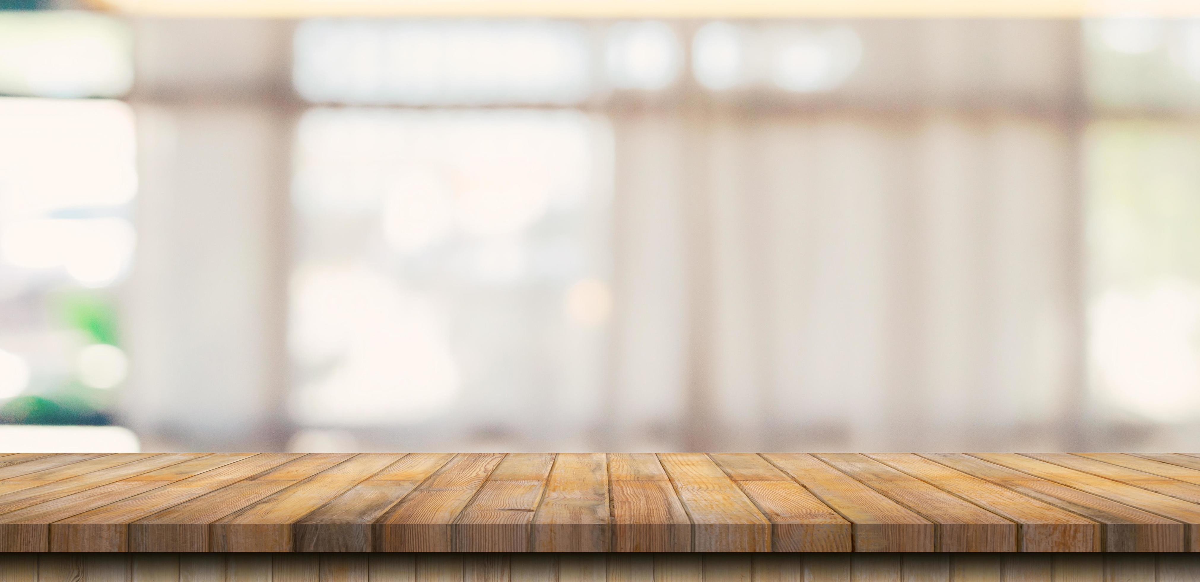 Wooden table top with blurred people in coffee shop and cafe background