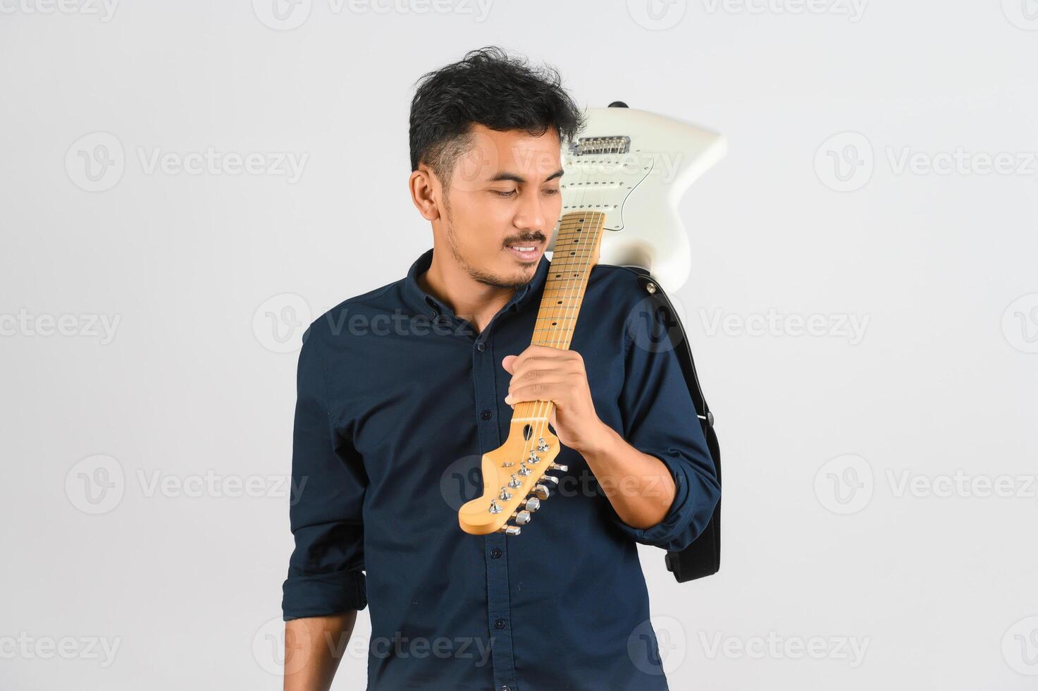 retrato de un joven asiático con camisa azul y guitarra electrónica aislado de fondo blanco foto