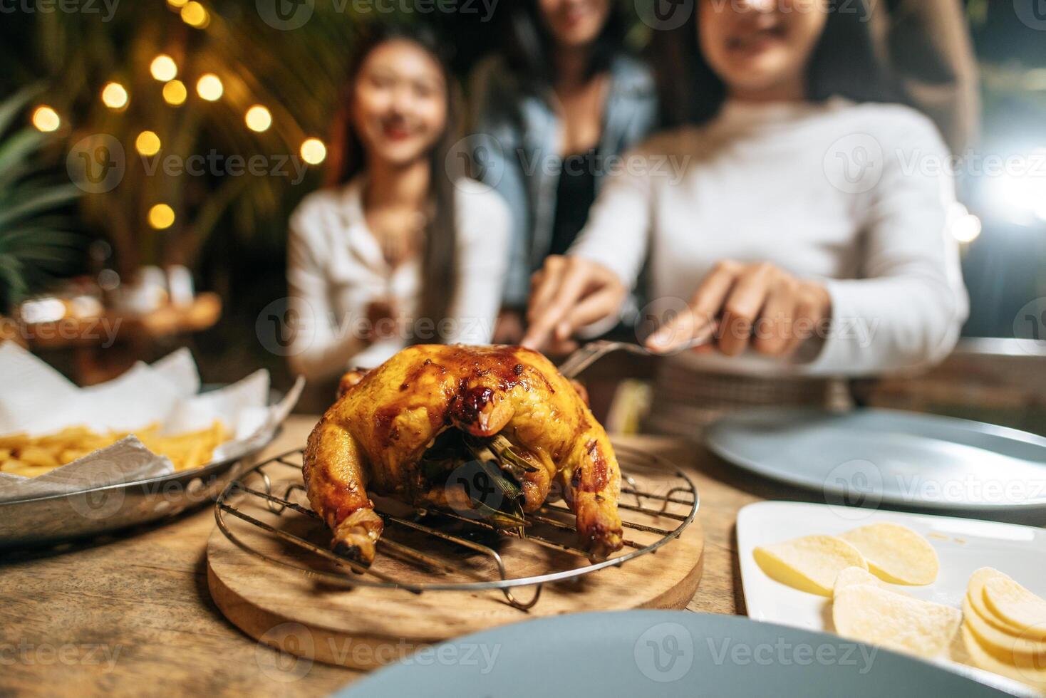 Happy Asian friends cheering with roasted turkey dinner outdoor - Group of people having fun in new year party. People, food and drink lifestyle concept Night Party, people and celebration concept. photo