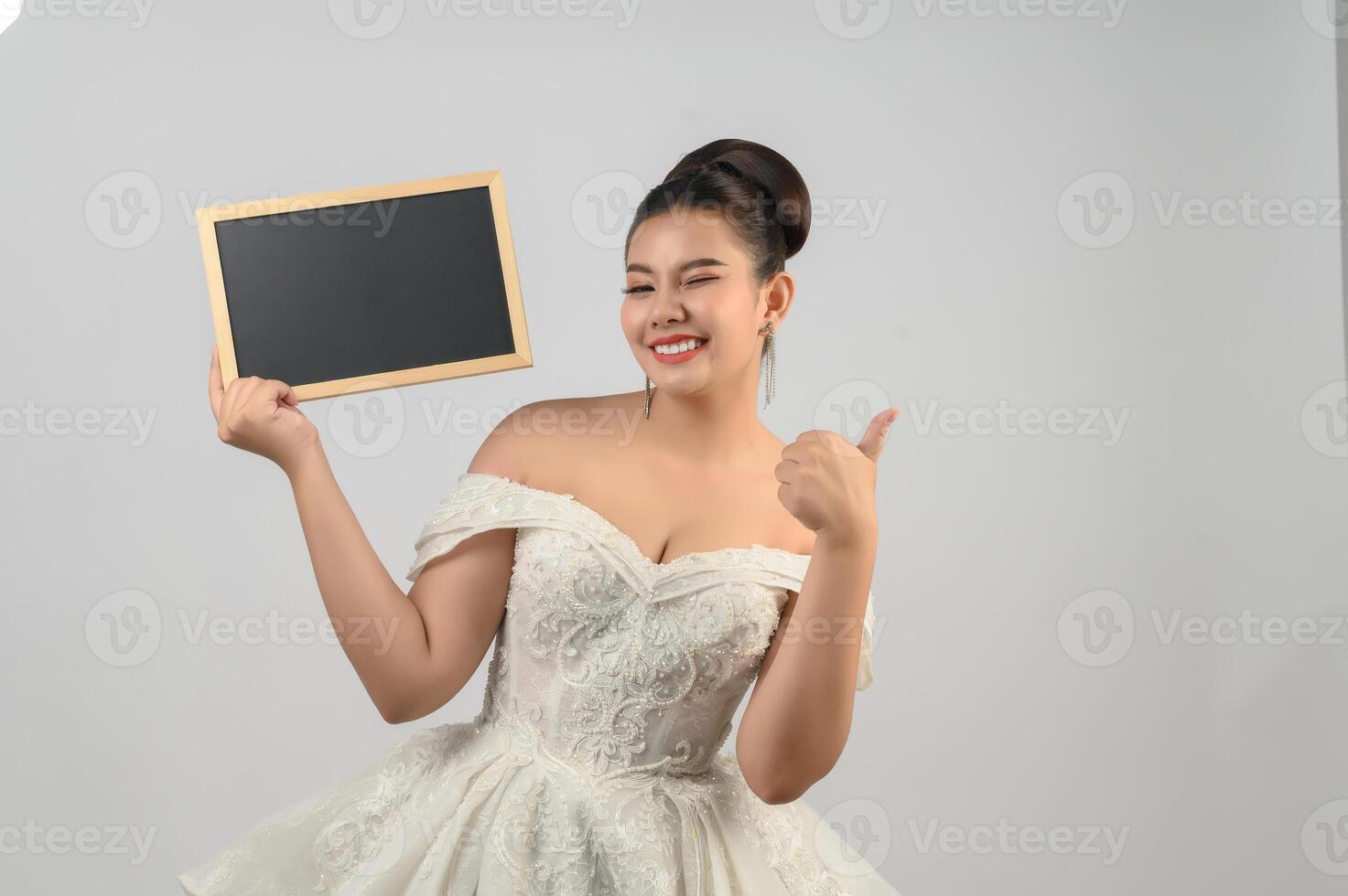 Una joven novia asiática hermosa posa con una pizarra en blanco en la mano foto