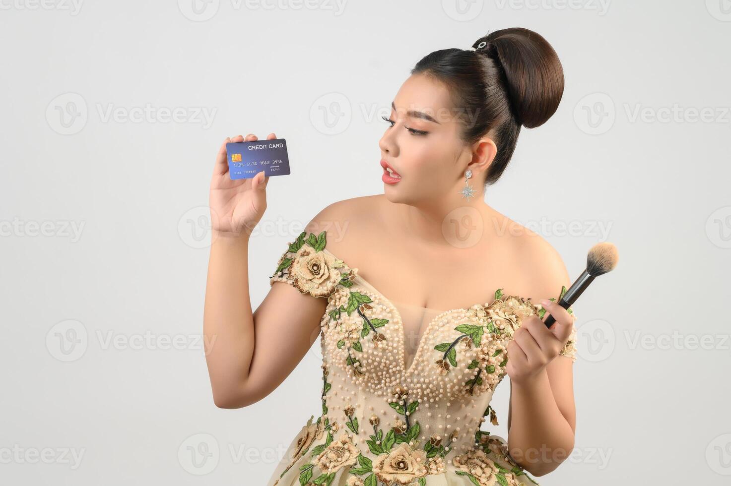 Young asian beautiful bride posting with credit card and beauty brush in hand photo