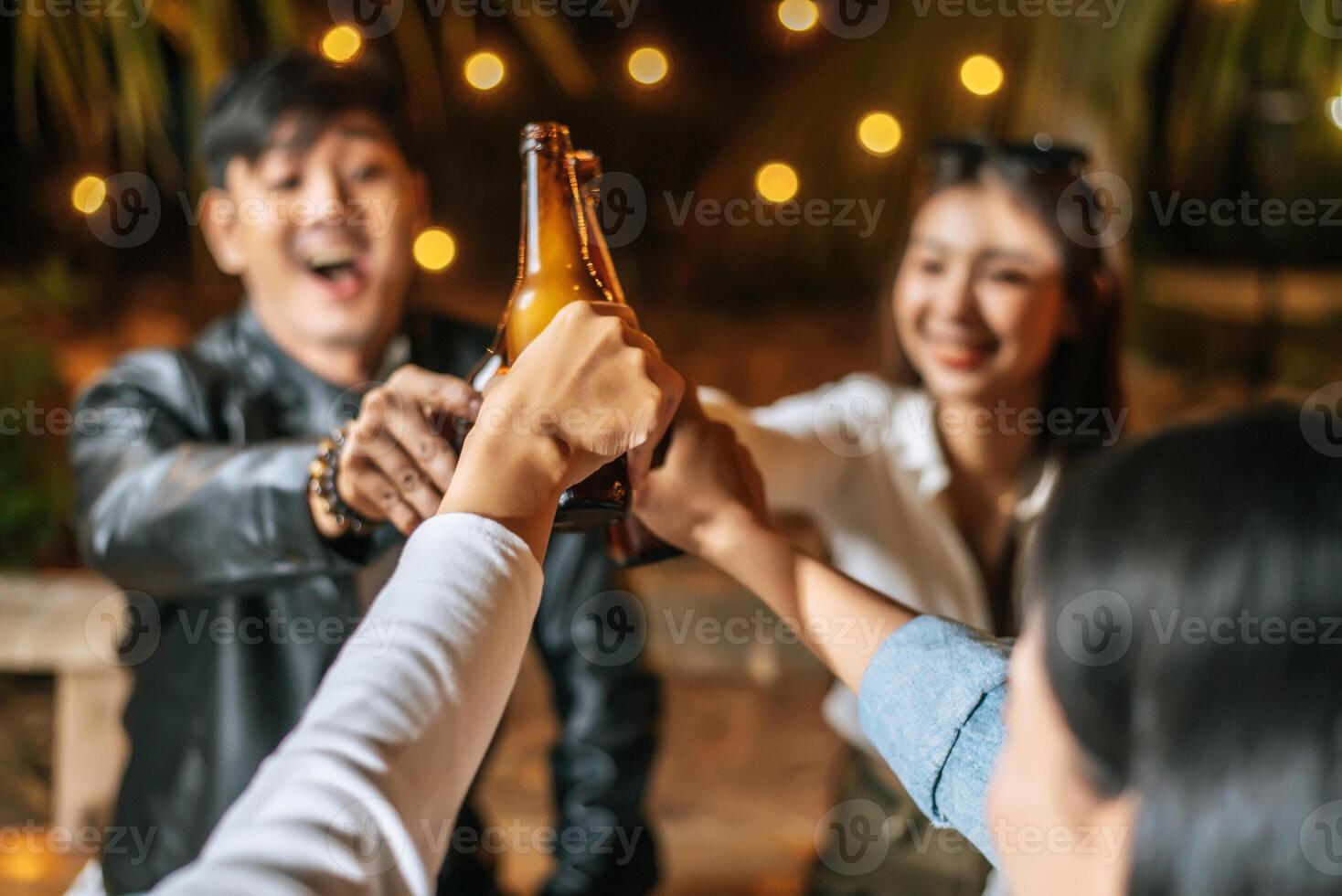 Portrait of Happy Asian friends having dinner party together - Young people sitting at bar table toasting beer glasses dinner outdoor  - People, food, drink lifestyle, new year celebration concept. photo