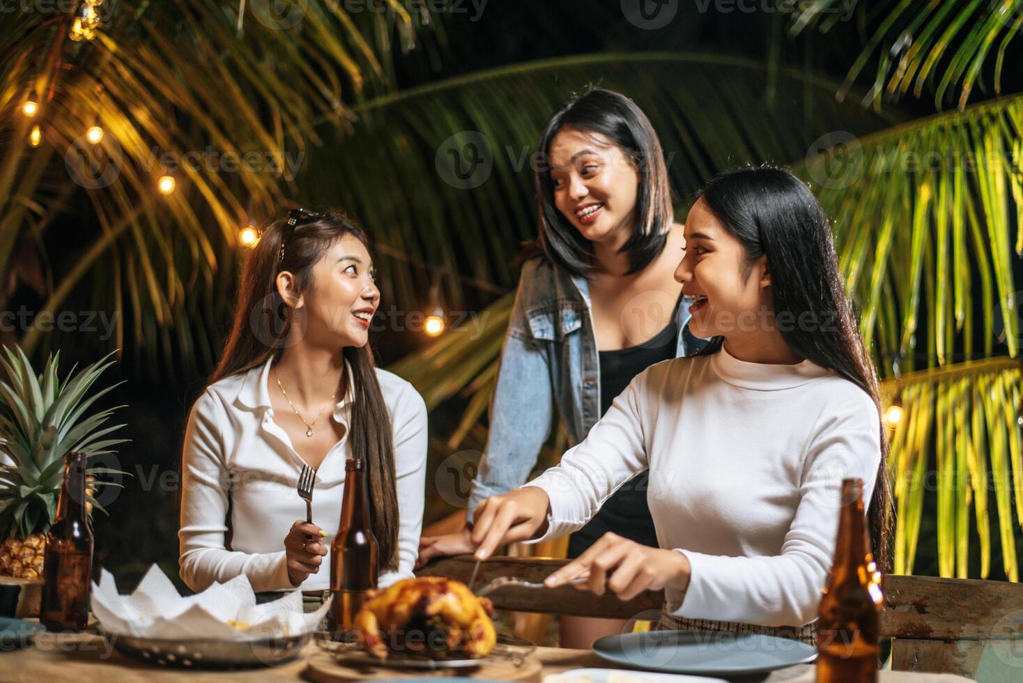 felices amigos asiáticos animando con una cena de pavo asado al aire libre - grupo de personas divirtiéndose en la fiesta de año nuevo. gente, comida y bebida concepto de estilo de vida fiesta nocturna, gente y concepto de celebración. foto