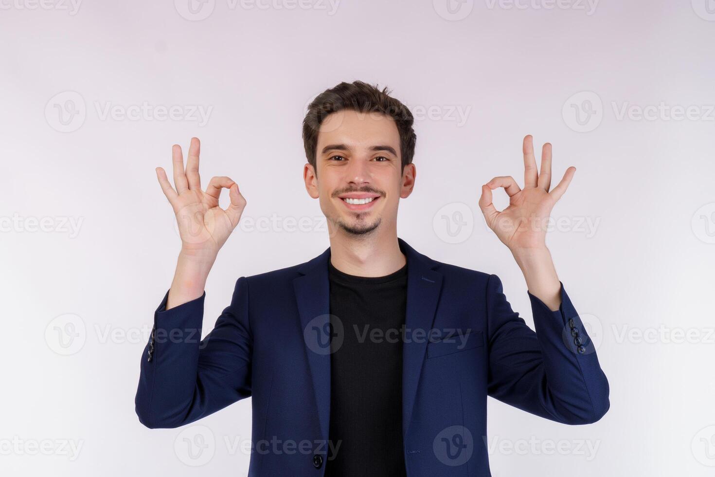 Portrait of happy young handsome businessman doing ok sign with hand and fingers over white background photo