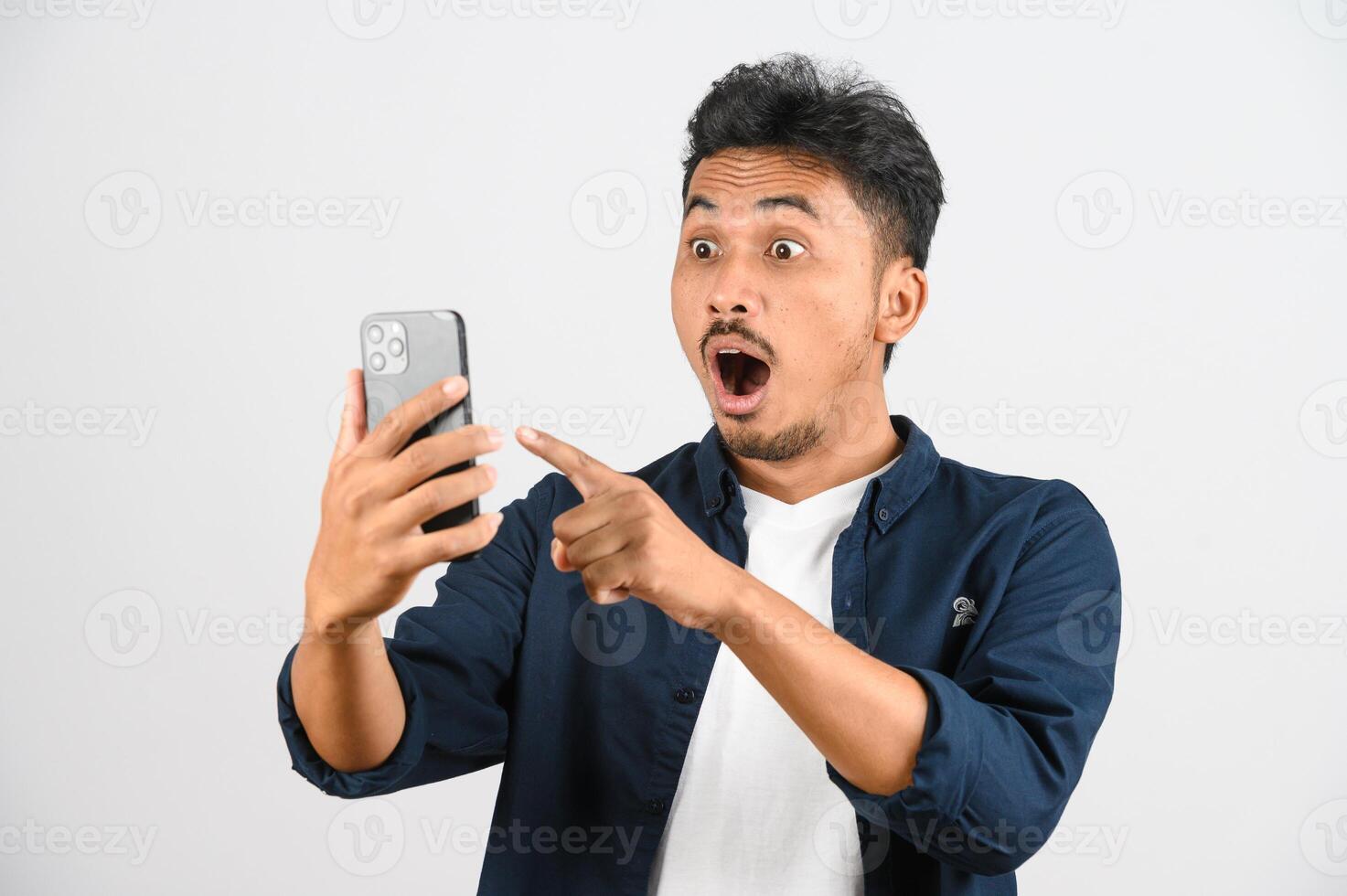 Protrait of Young asian man expressing surprise while using mobile phone isolated over white background photo