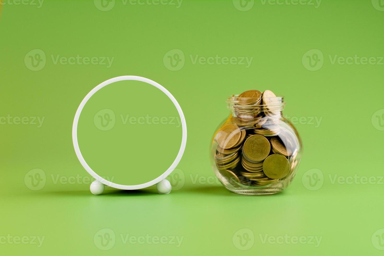 Saving gold coins in glass jars on green background, coin savings concept photo