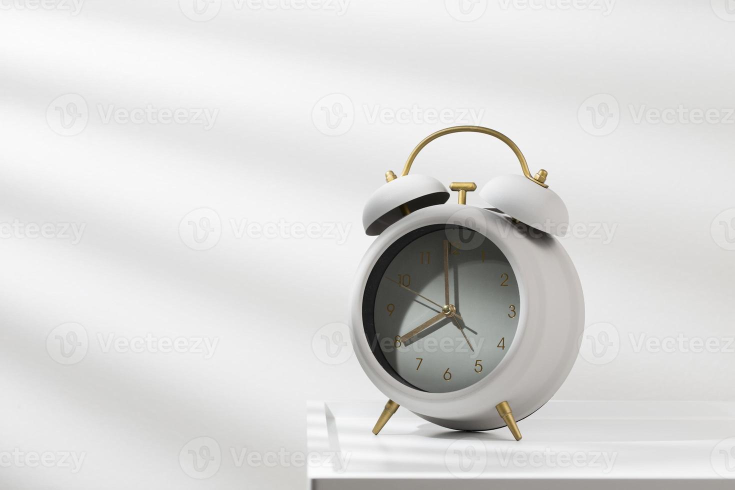 Minimalist gray alarm clock on the wooden table and morning light. photo