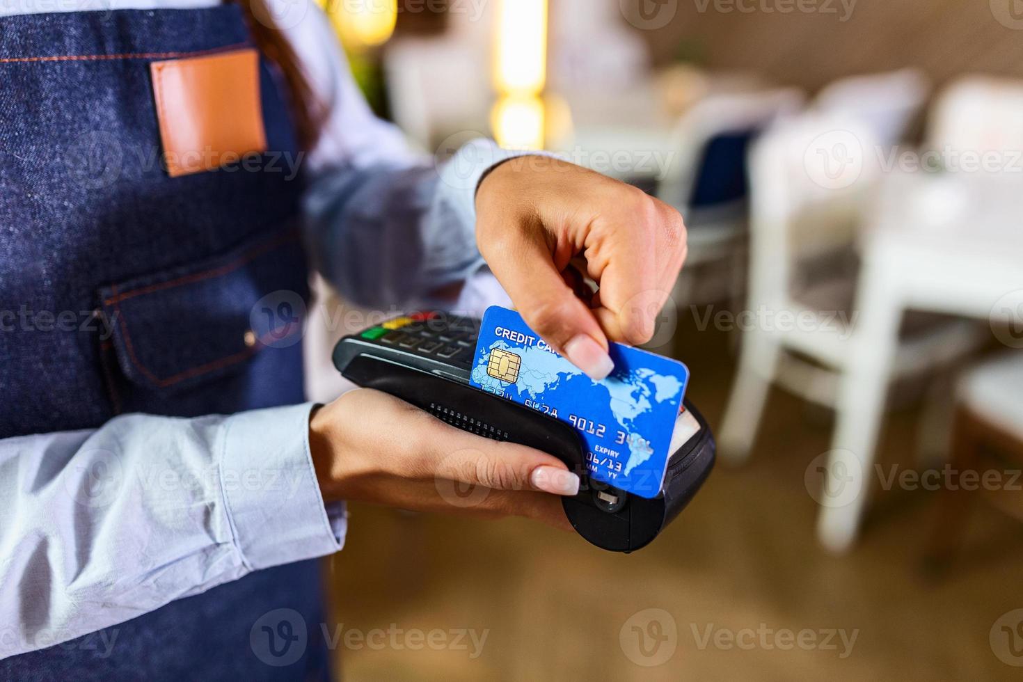 Contactless payment concept, female holding credit card near nfc technology on counter, client make transaction pay bill on terminal rfid cashier machine in restaurant store, close up view photo