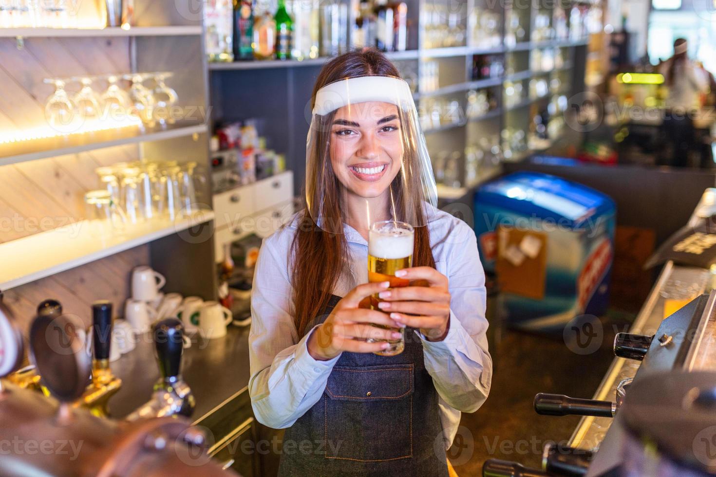 Bartender with face shield covid-19 protection, serving a draft beer at the bar counter during coronavirus pandemic, shelves full of bottles with alcohol on the background photo
