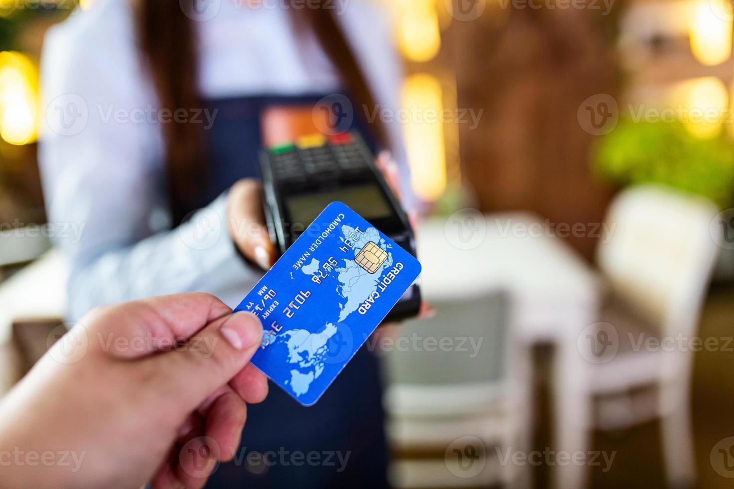 Contactless payment concept, female holding credit card near nfc technology on counter, client make transaction pay bill on terminal rfid cashier machine in restaurant store, close up view photo