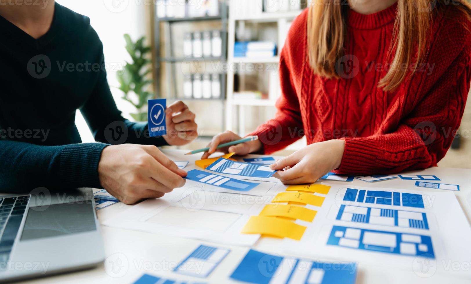 UX developer and ui designer brainstorming about mobile app interface wireframe design with customer breif and color code at office. photo