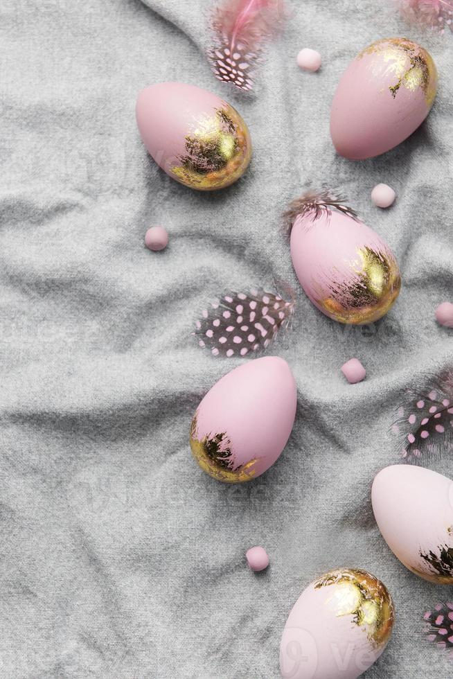 Easter eggs are painted with violet and gold paint on a gray linen background. photo