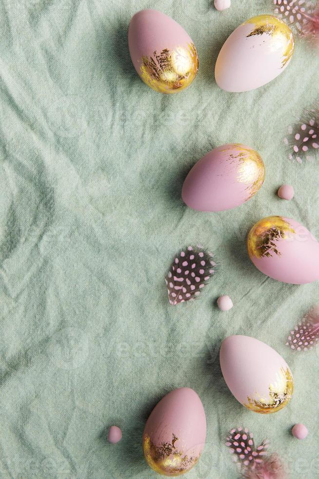 los huevos de pascua están pintados con pintura violeta y verde sobre un fondo de lino gris. foto