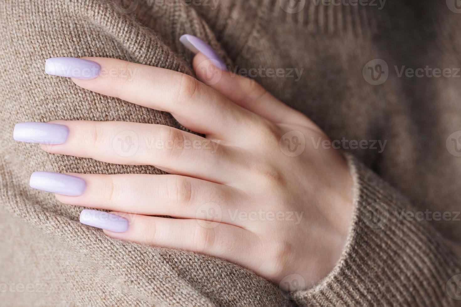 manos de niña con una manicura violeta suave. foto