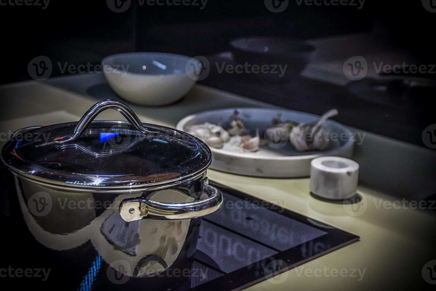 A modern kitchen top with a steel pot, dishes and garlic photo