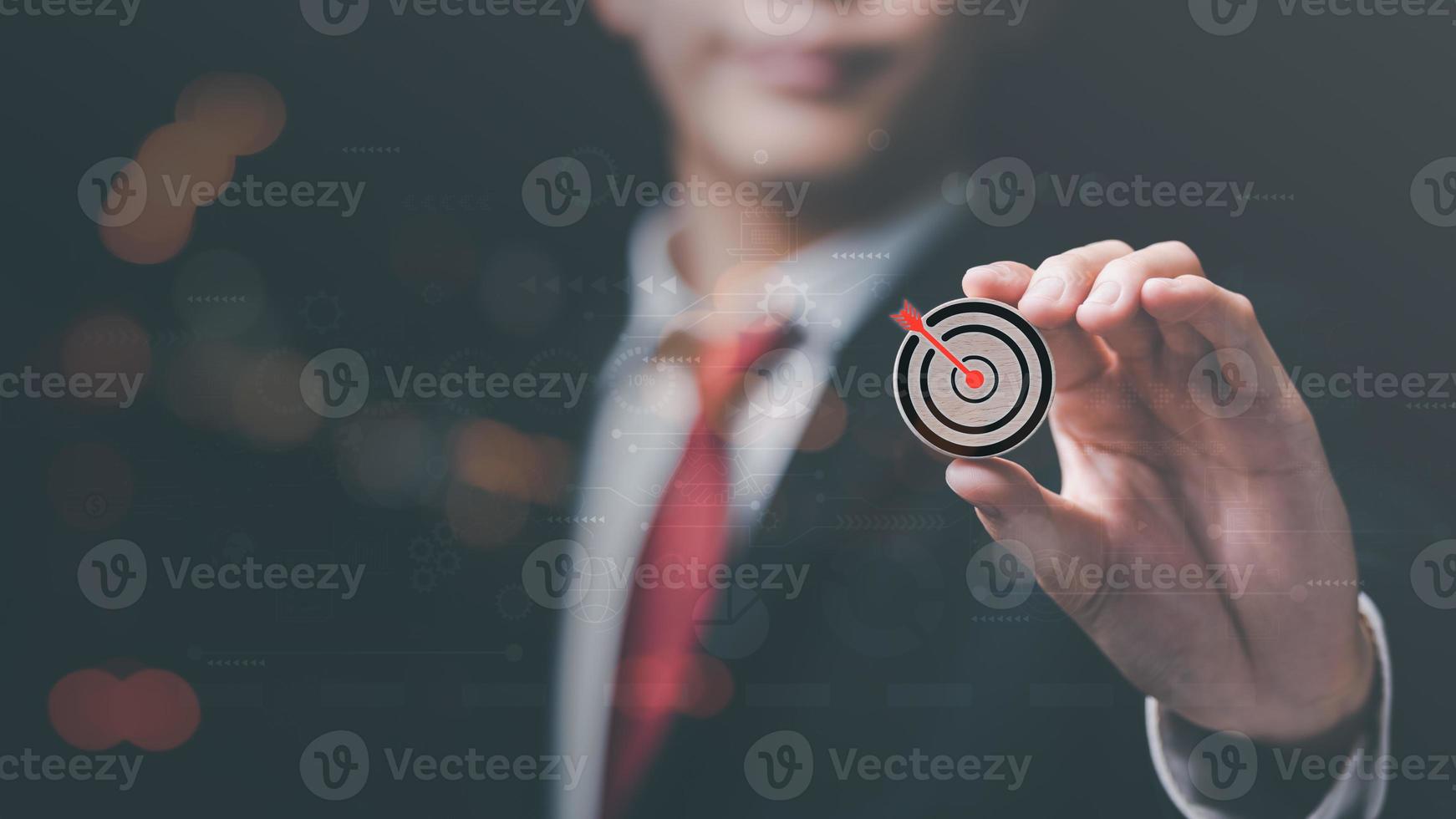 Wooden block in businessman hand and arrow icon hitting center of dartboard target,Setting business goals and focused concepts, Organizational growth and objectives, marketing strategy planning photo